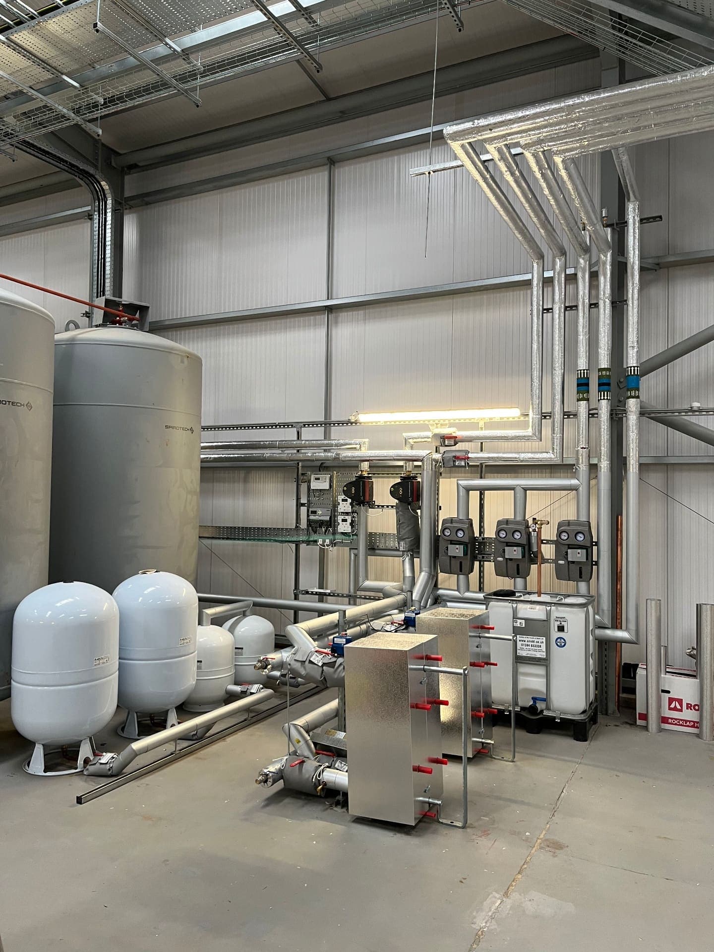 Commercial plant room with buffer vessels, pumps and a plate heat exchanger