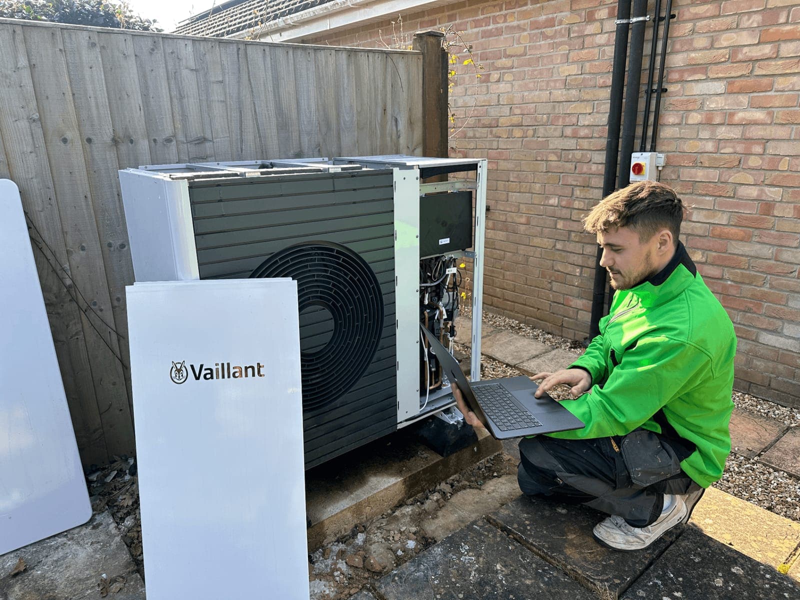 Solwat engineer commissioning a Vaillant air source heat pump with a laptop